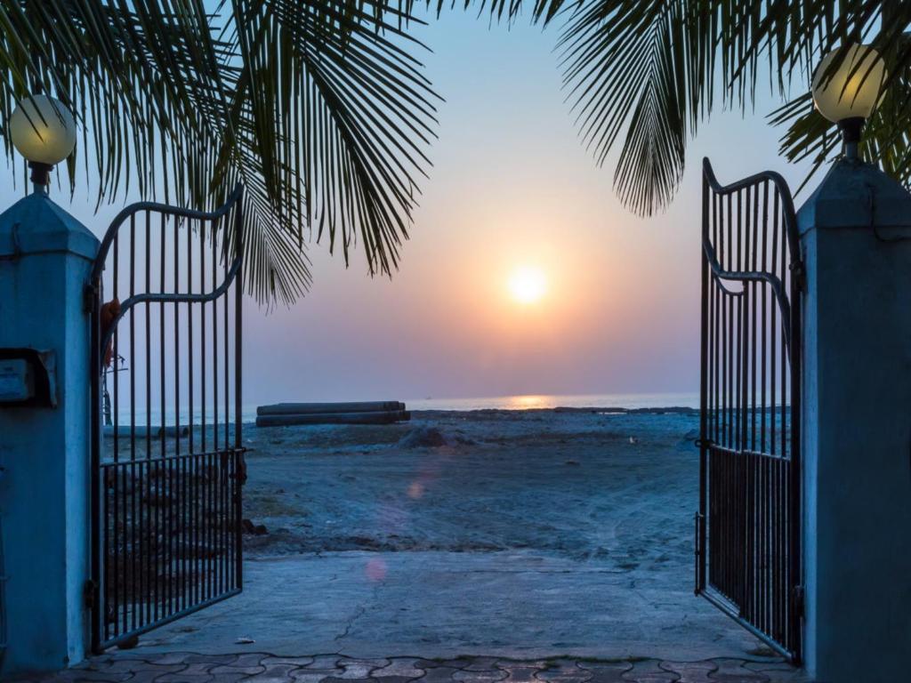 an open gate to the beach at sunset at SaffronStays Salt Rim on the Beach, Korlai in Christpāda