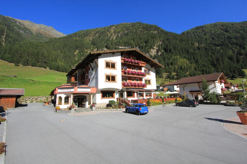 ein großes Gebäude mit Autos auf einem Parkplatz in der Unterkunft Alpenhof Pitztal in Sankt Leonhard im Pitztal