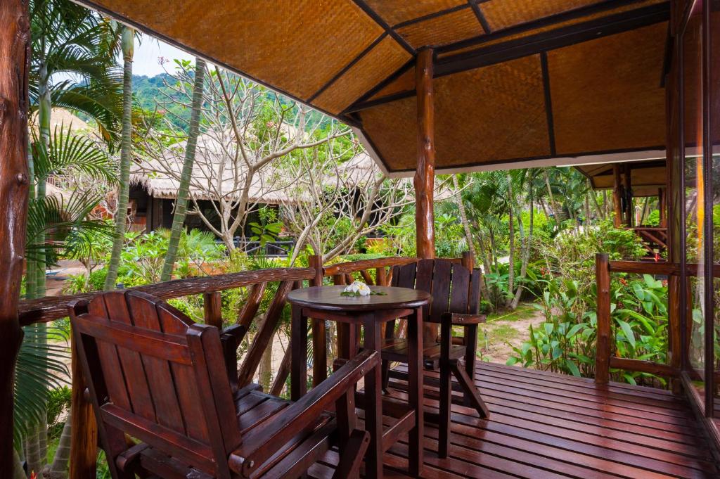 a wooden deck with a table and chairs on it at Palm Leaf Resort Koh Tao in Ko Tao