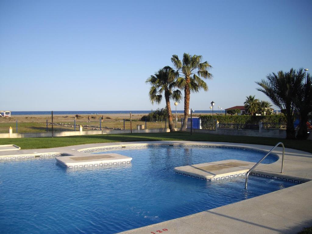 a large swimming pool next to a beach with palm trees at Residencial Veramar 4, Vera Playa, Almeria in Vera
