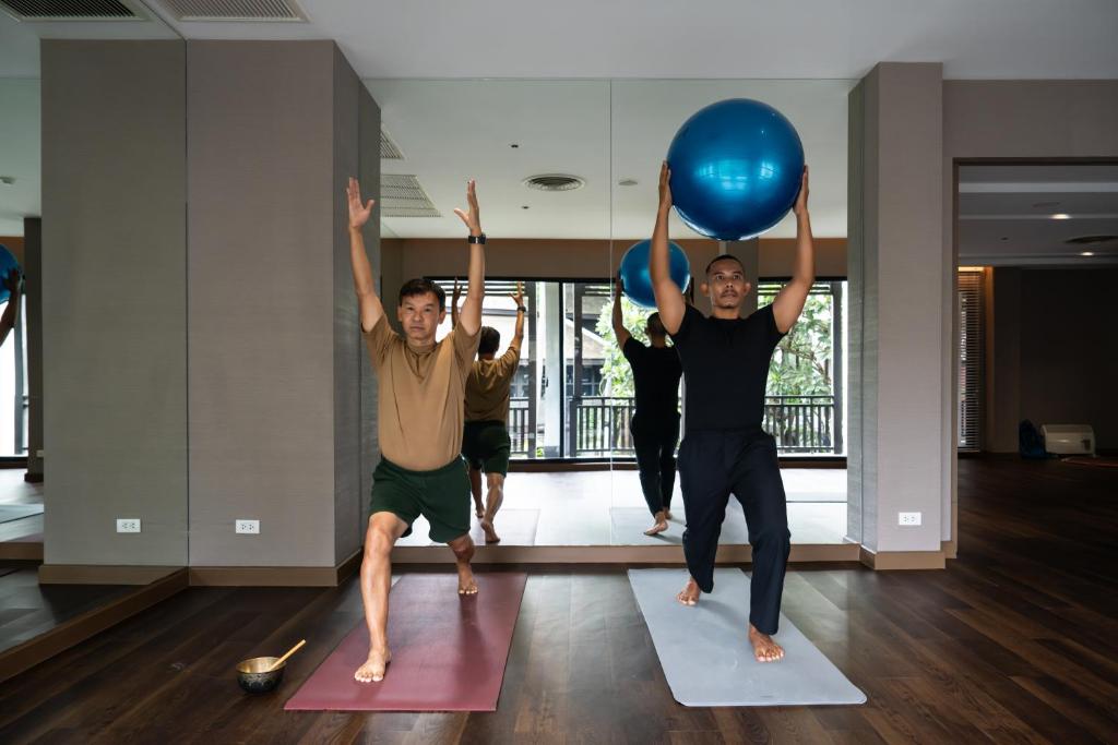 A mirrored fitness studio where a small group practises a ball-based exercise.