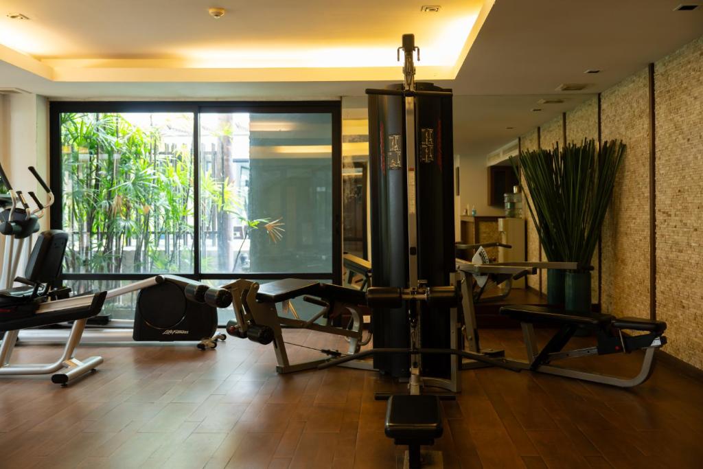 A bright fitness room combines cardio machines, weight equipment and a garden-facing window.