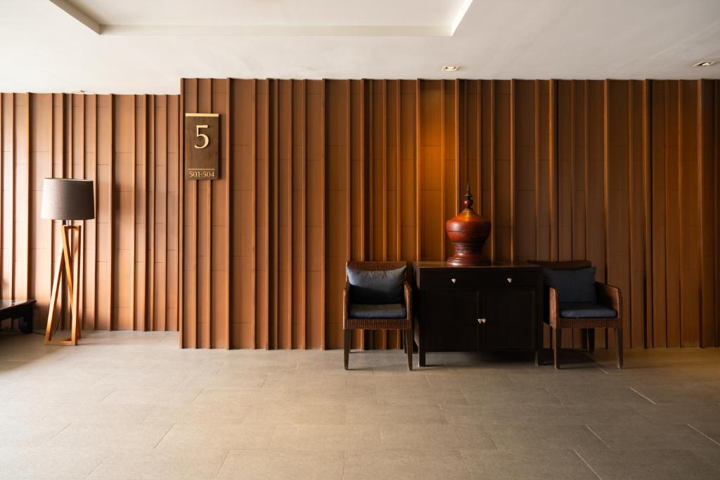 Two armchairs and a small cabinet create a quiet seating nook against a dramatic wood-paneled wall.