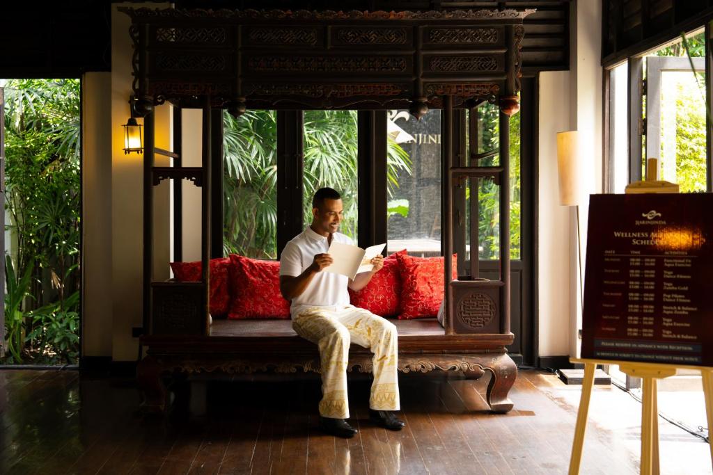 A carved wooden bench sits beside tall windows in a warmly lit interior.