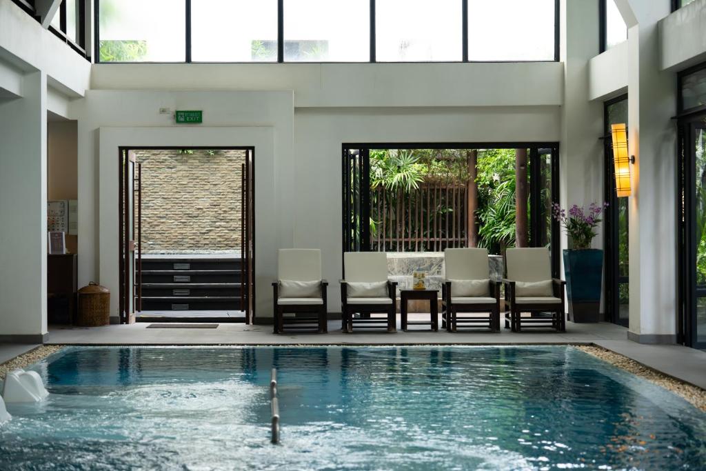 An indoor pool sits beneath high windows with lounge chairs along the far side.