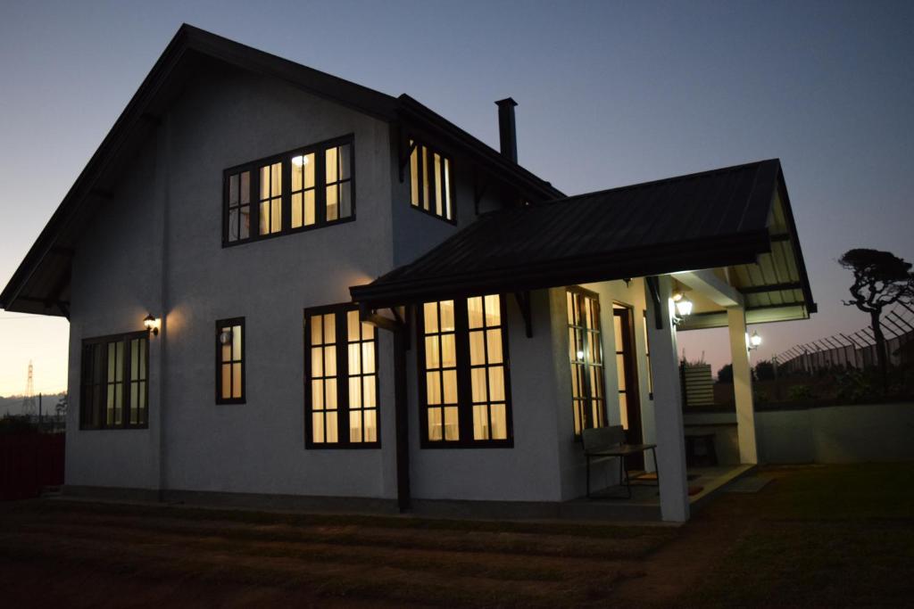 a house with lights on in the evening at Beraliya Cottage in Nuwara Eliya