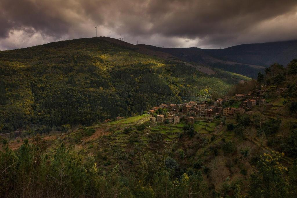 ein kleines Dorf auf einem Hügel mit einem Kreuz oben in der Unterkunft Talasnal Montanhas de Amor in Lousã