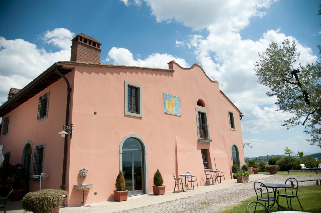a pink building with tables and chairs in front of it at Le Fonti A San Giorgio in Montespertoli