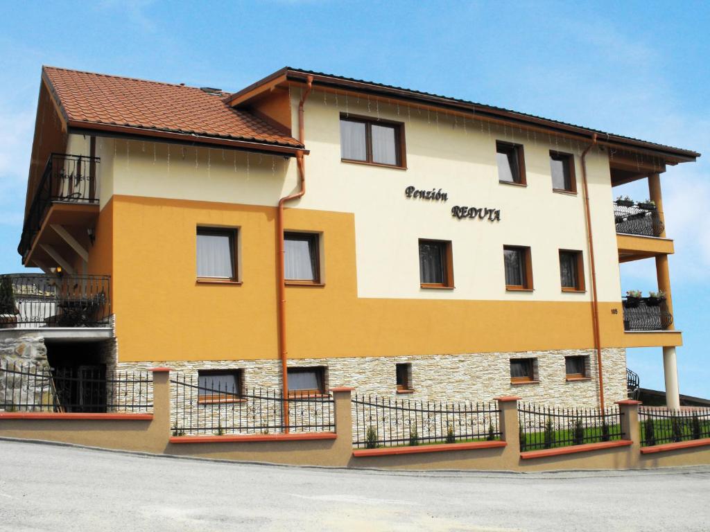 a yellow and white building with a brown roof at Penzión Reduta in Oravský Podzámok