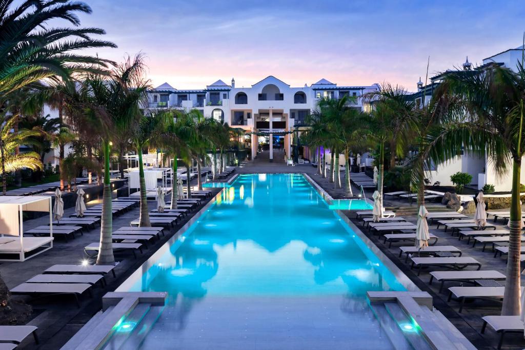 a pool at the resort with chaise lounges and palm trees at Barceló Teguise Beach - Adults Only in Costa Teguise