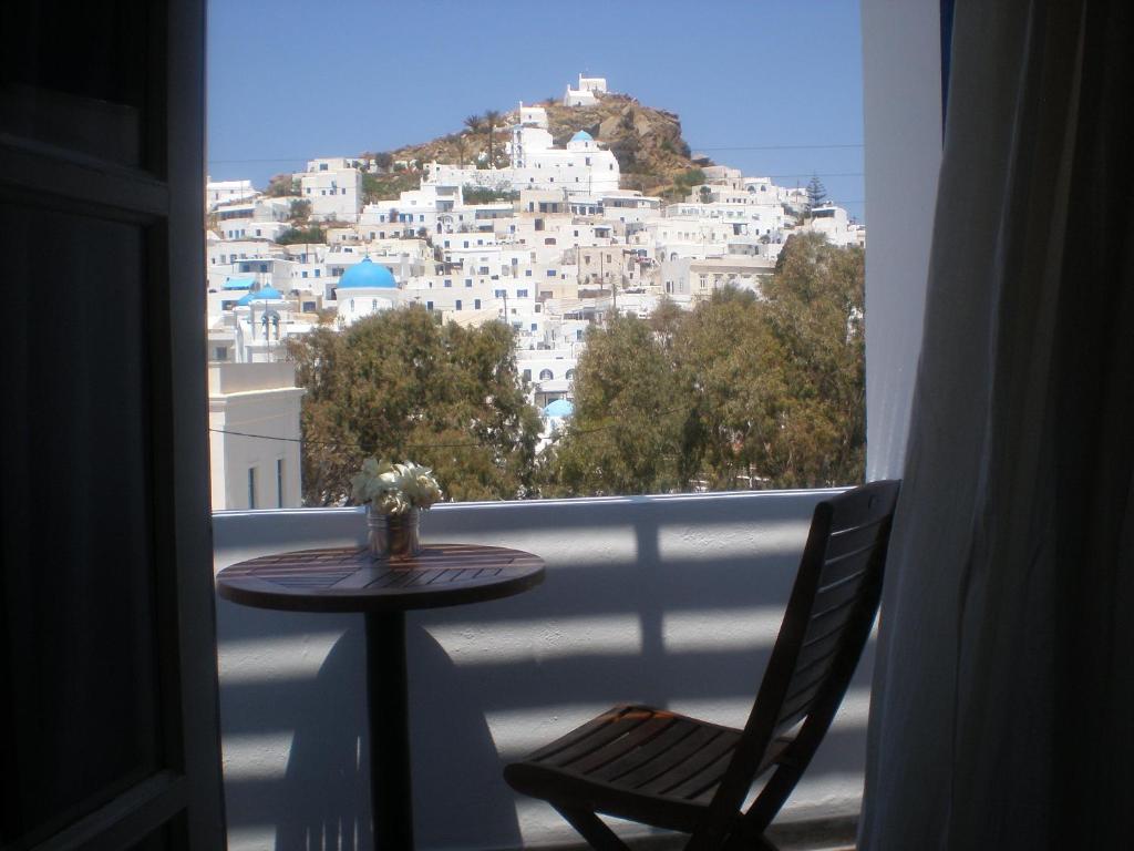 a table and chair on a balcony with a view of a city at Armonia Pension in Ios Chora