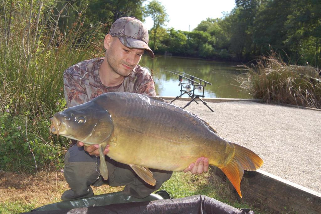 a man holding a large fish in front of a river at Lac de la Vie in Bressuire