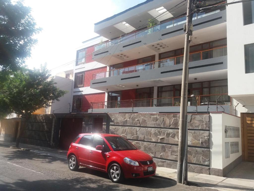 un coche rojo estacionado frente a un edificio en Miraflores, en Lima