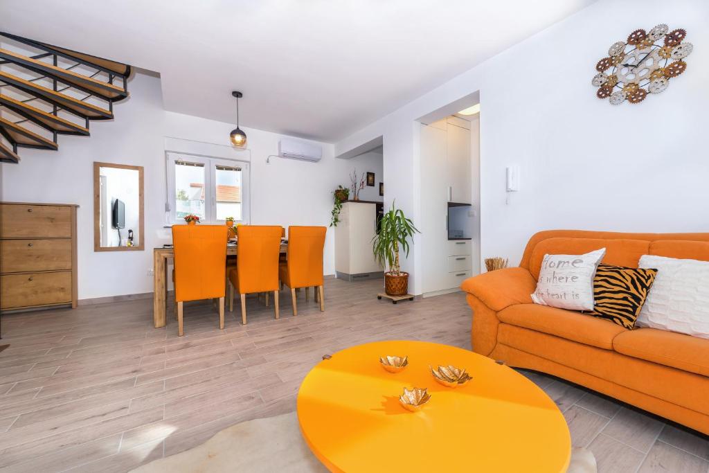 Apartment Marita في زابوريتش: غرفة معيشة مع أريكة برتقالية وطاولة