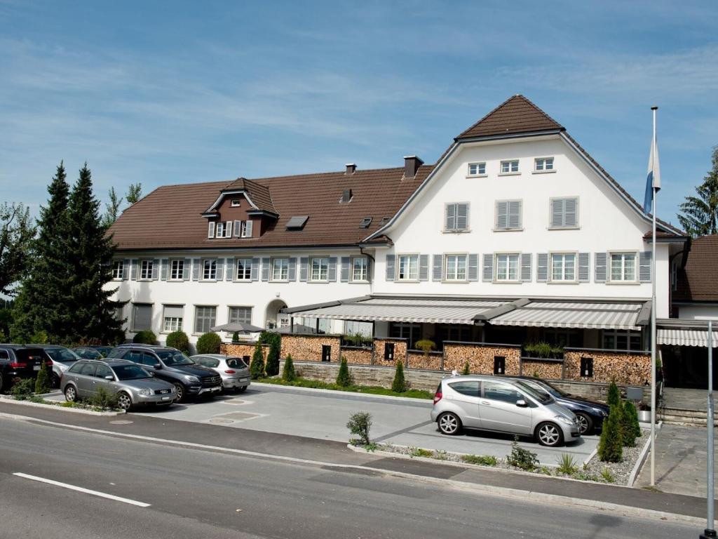 un grand bâtiment blanc avec des voitures garées dans un parking dans l'établissement Hotel & Gasthaus Die Perle, à Perlen