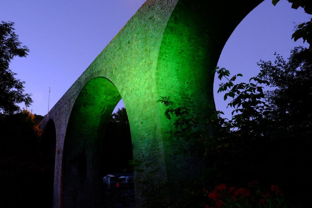 a green lit up bridge in the dark at Maison Sous Le Pont in Meyras