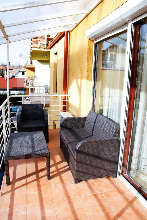 balkon z 2 krzesłami, kanapą i stołem w obiekcie Princess Luxus Apartman w Siófoku