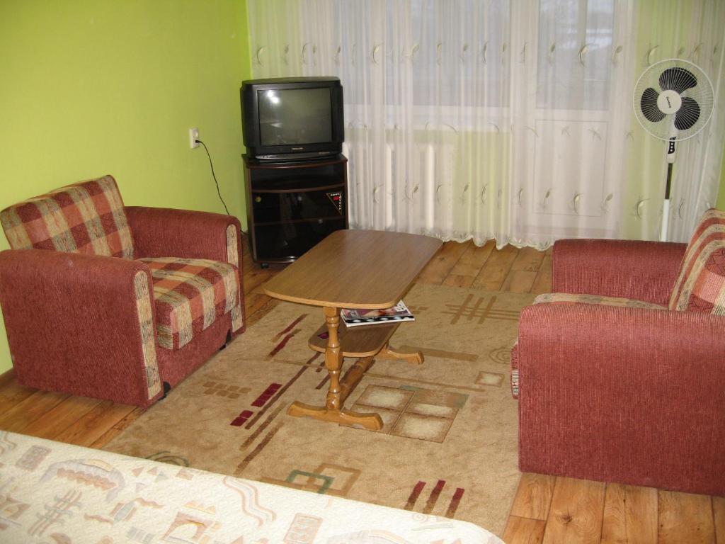 sala de estar con 2 sillas, mesa y TV en Apartment on Vasylya Chervoniya 67 en Rivne
