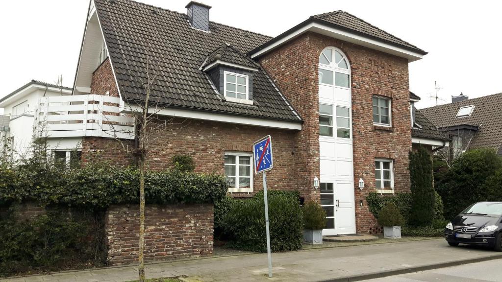 uma casa de tijolos com um sinal de estacionamento em frente em Meerbusch Apartments - 20 Min Messe DUS em Meerbusch