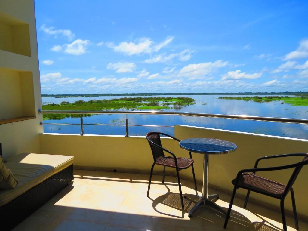 balcón con mesa, sillas y vistas al agua en Boulevard 251 Riverside Apartments, en Iquitos