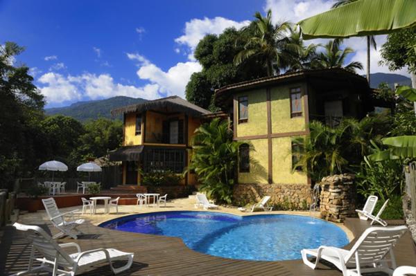 a house with a swimming pool in front of a house at Pousada Villaggio Assis in Ilhabela