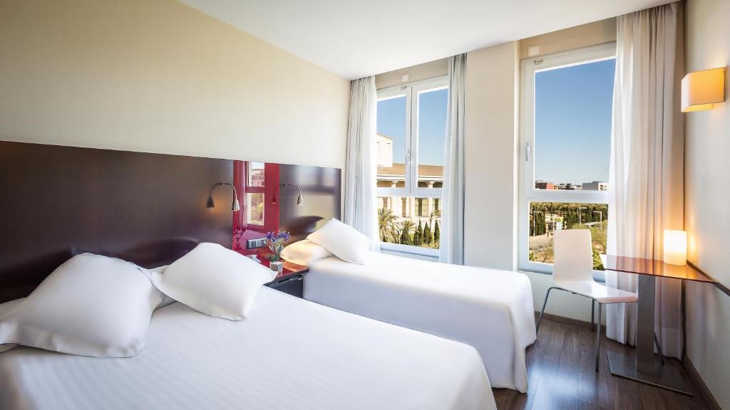 a hotel room with two beds and two windows at SM Hotel Teatre Auditori in Barcelona