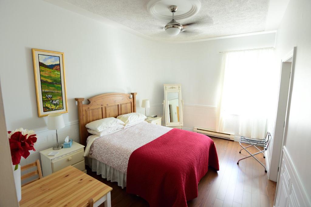 a bedroom with a bed with a red blanket at Auberge le St-Georges in Saguenay