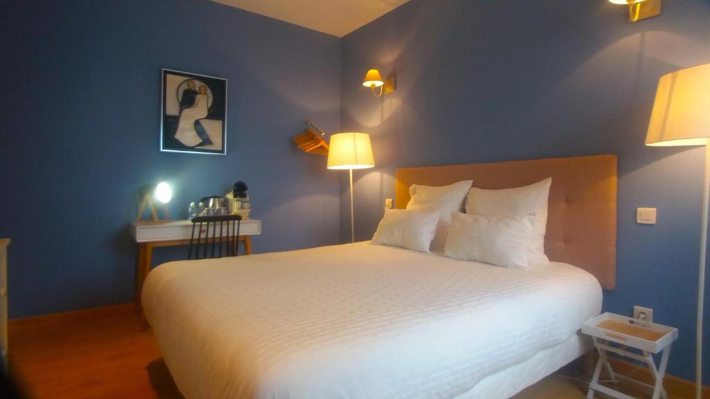 - une chambre avec un grand lit blanc aux murs bleus dans l'établissement Le Nautilus, à Wimereux