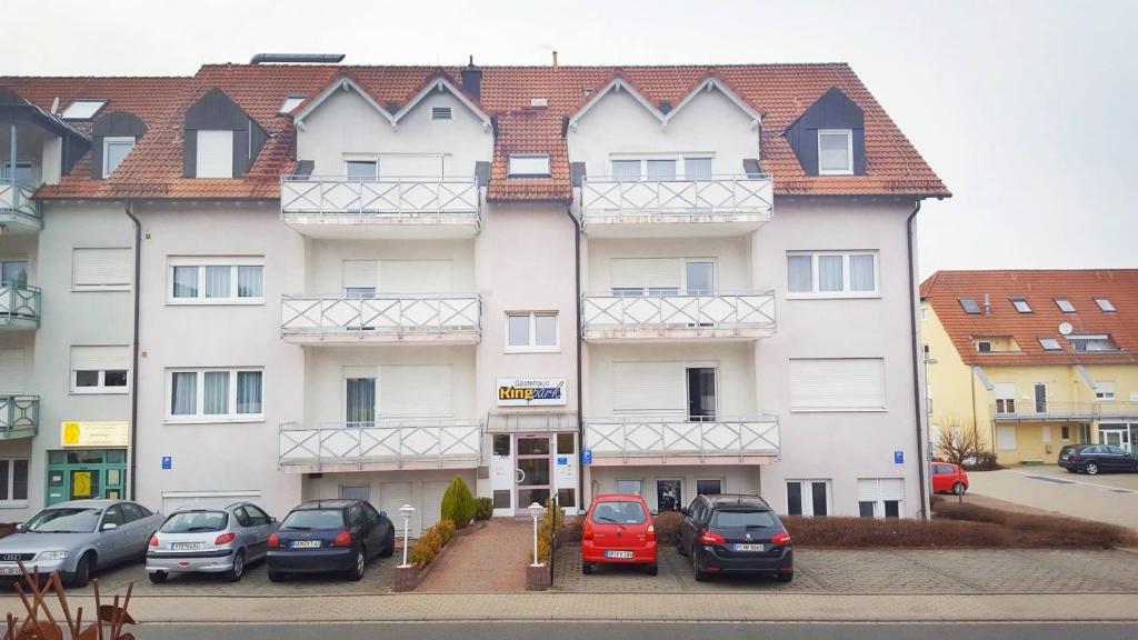 ein großes weißes Gebäude mit Autos auf einem Parkplatz in der Unterkunft Hotel Ring Park in Buchen