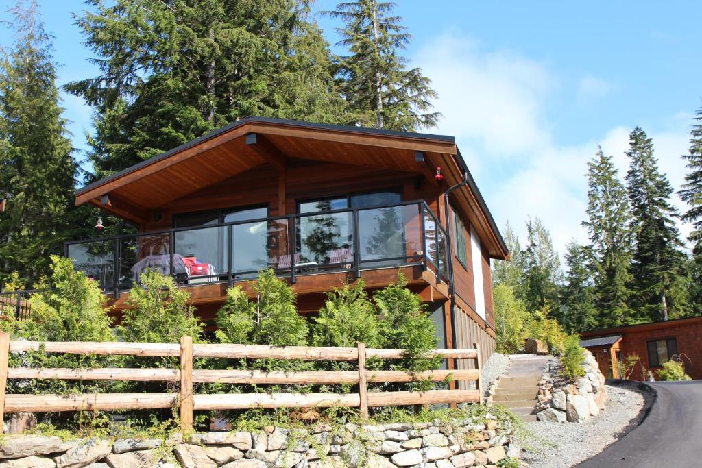 a house in the woods with a wrap around porch at Tilby's Rainbow Cottage in Port Renfrew