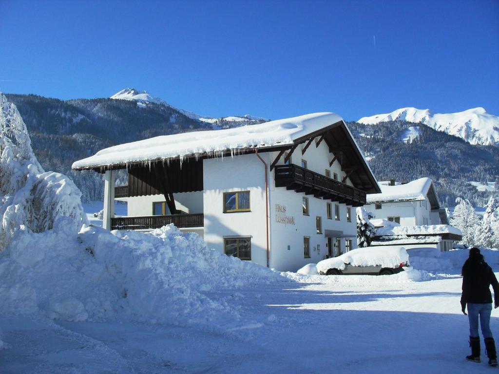 uma pessoa em pé em frente a um edifício coberto de neve em Haus Lusspark em Lermoos