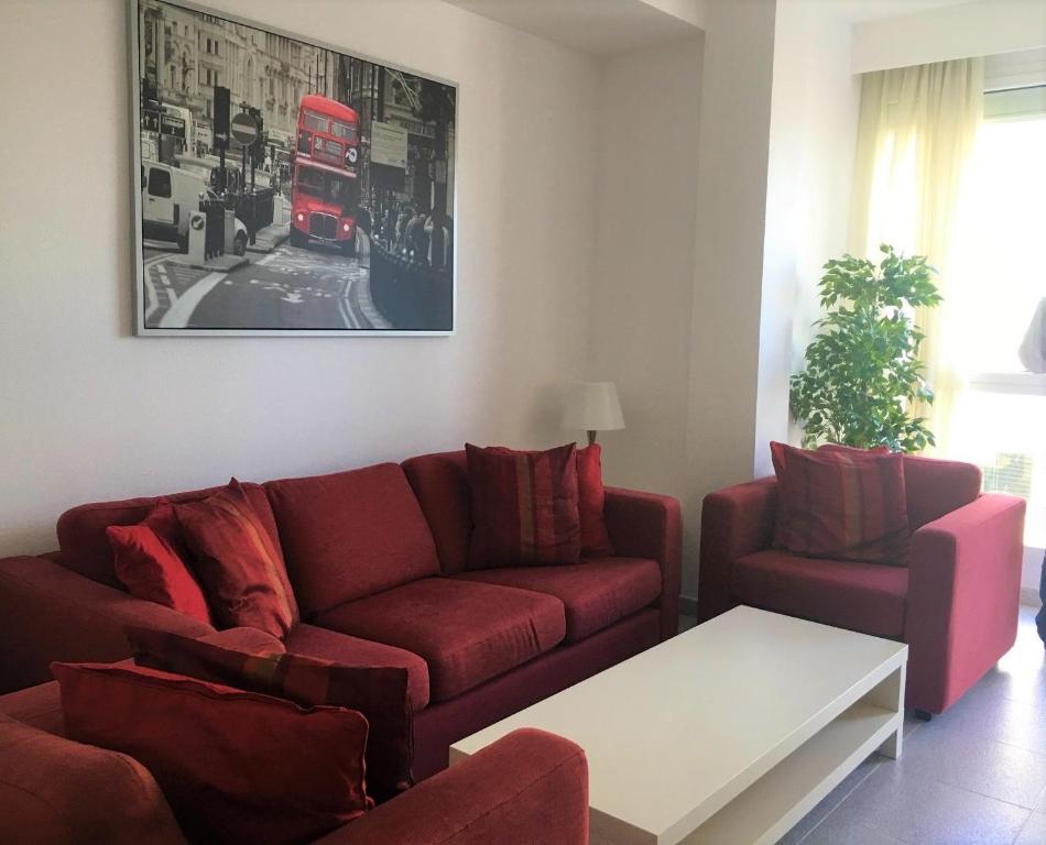 a living room with a red couch and two chairs at Venegas Home in Las Palmas de Gran Canaria