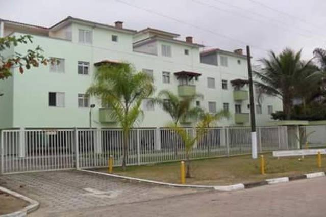 a white building with a fence and palm trees at Ubatuba Apartamento Maurilio in Ubatuba