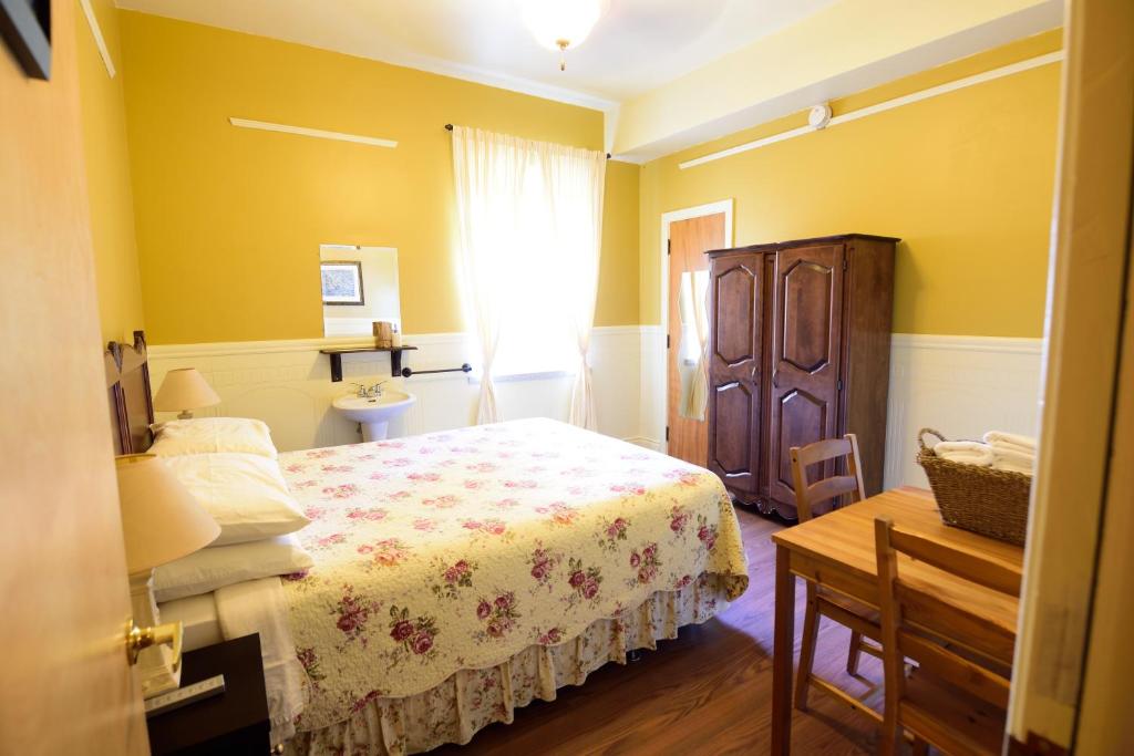 a bedroom with a bed and a table and a window at Auberge le St-Georges in Saguenay