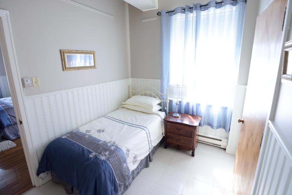 a small bedroom with a bed and a window at Auberge le St-Georges in Saguenay