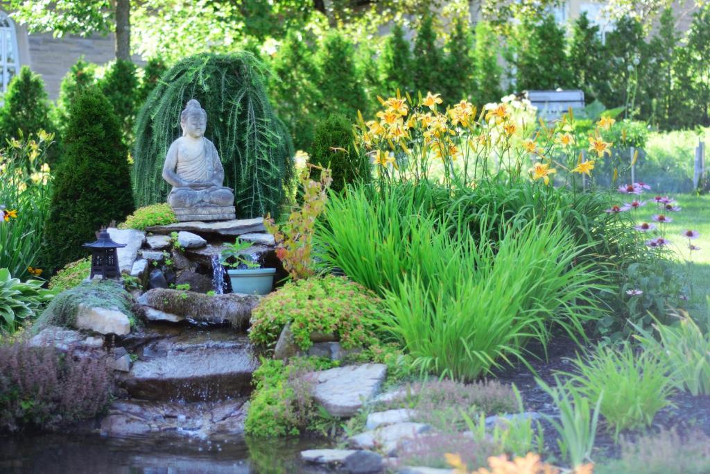 a garden with a statue in the middle of a pond at Auberge le St-Georges in Saguenay