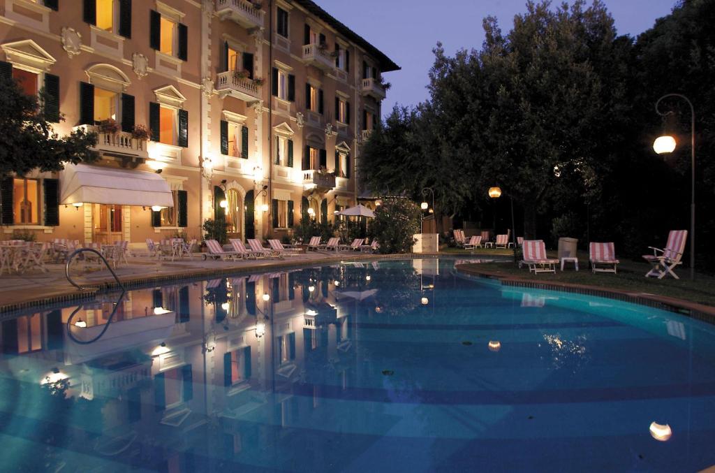 una piscina di fronte a un edificio di notte di Grand Hotel Bellavista Palace & Golf a Montecatini Terme