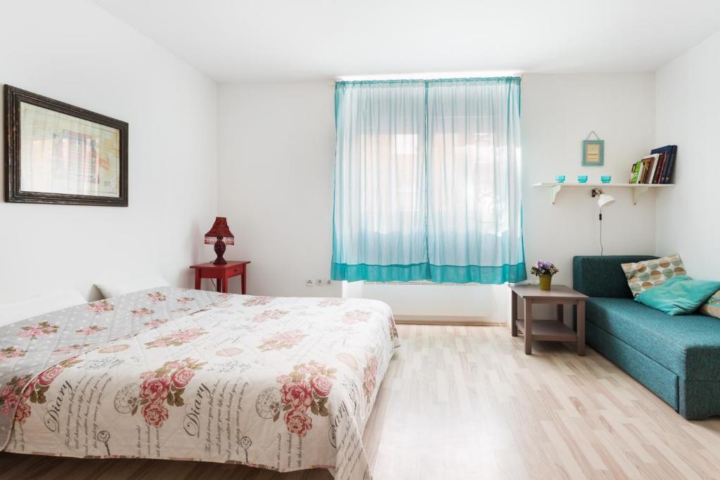 - une chambre avec un lit et un canapé bleu dans l'établissement Apartment Roza, à Zagreb