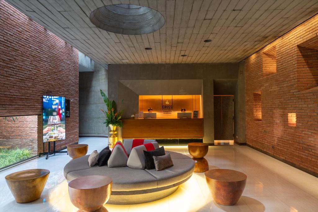 A warmly lit hotel lobby with a circular upholstered sofa facing the reception desk.
