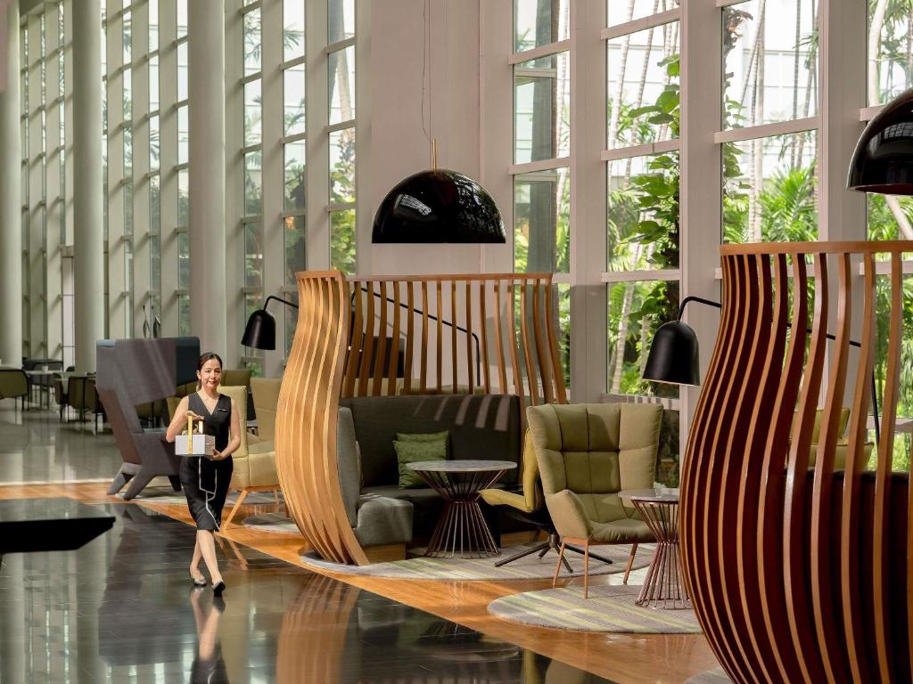 A tall, sunlit lobby lounge with sculptural wooden screens and varied seating.