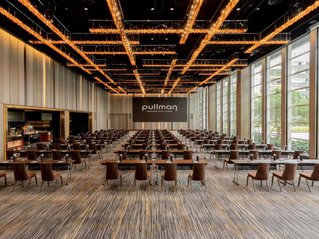 A large, bright dining hall arranged with many tables beneath a striking illuminated ceiling.