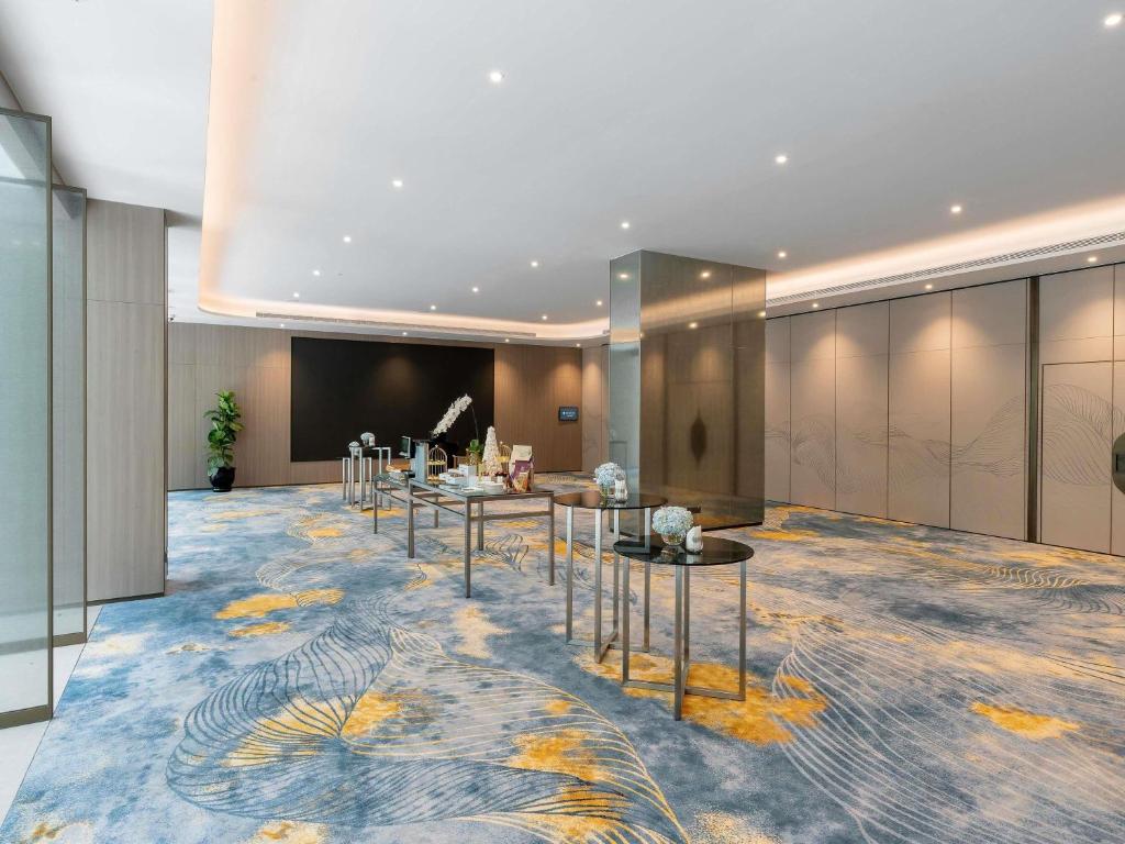 A spacious event foyer with a patterned carpet, presentation tables and enclosed meeting-room doors.