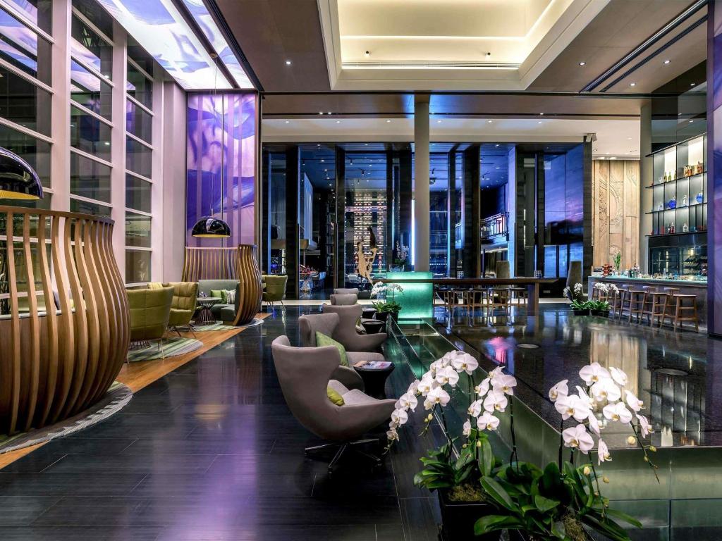 A dramatic lobby lounge and bar with reflective floors and purple lighting.