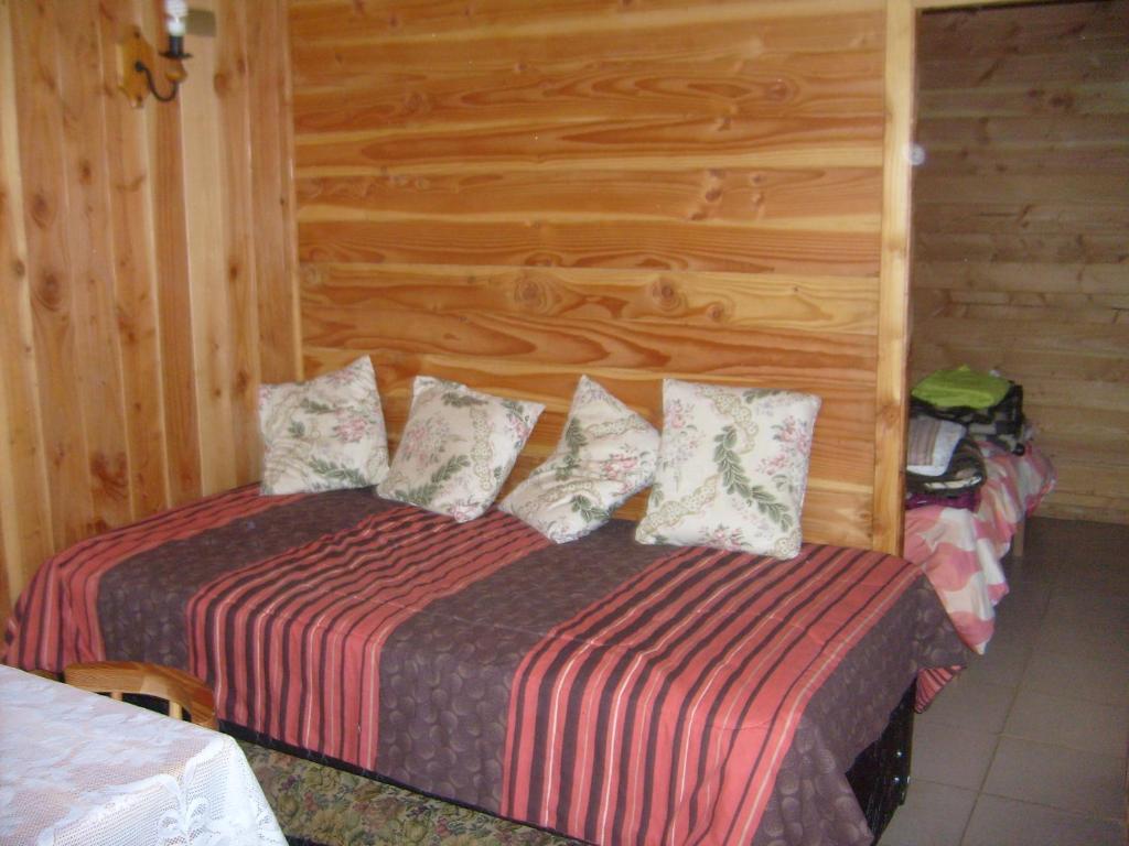 a bedroom with a bed and a wooden wall at Cabañas Los Castaños in Licán Ray