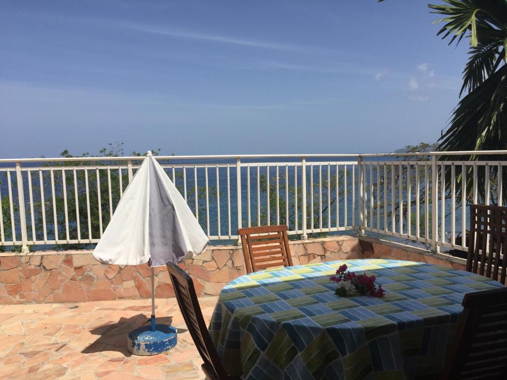 a table with an umbrella and chairs on a balcony at BRIN d AMOUR COTE ATLANTIQUE voir site vacances en martinique in La Trinité