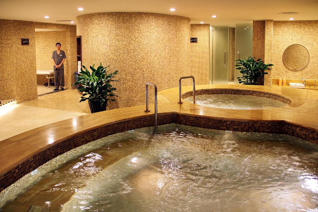 a jacuzzi tub in a hotel room with a man in the background at Central Hotel Shanghai in Shanghai
