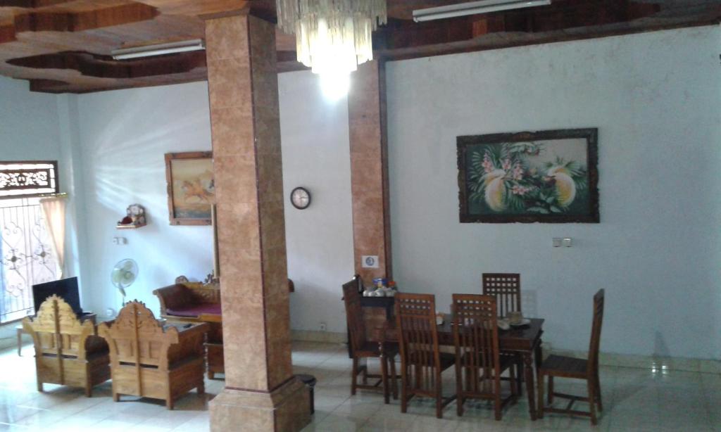 una sala da pranzo con tavolo, sedie e pilastro di Ratih Bali Hostel a Denpasar