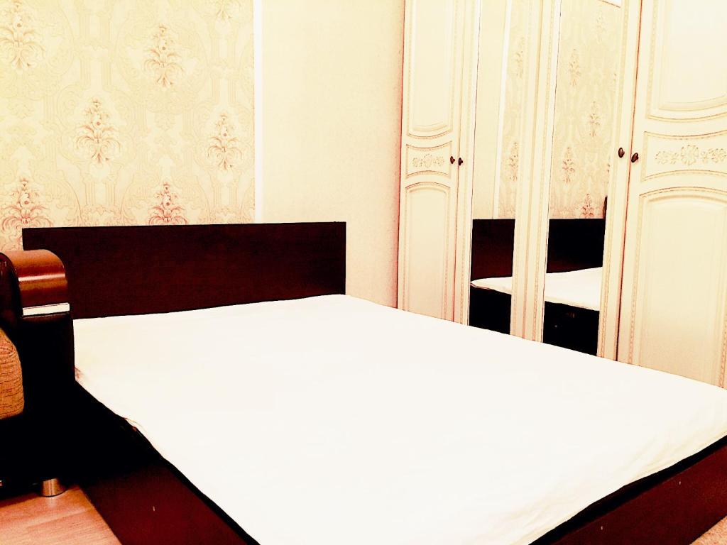 - une chambre avec 2 lits et des draps blancs dans l'établissement Vremena Goda Apartment in Astana, à Astana