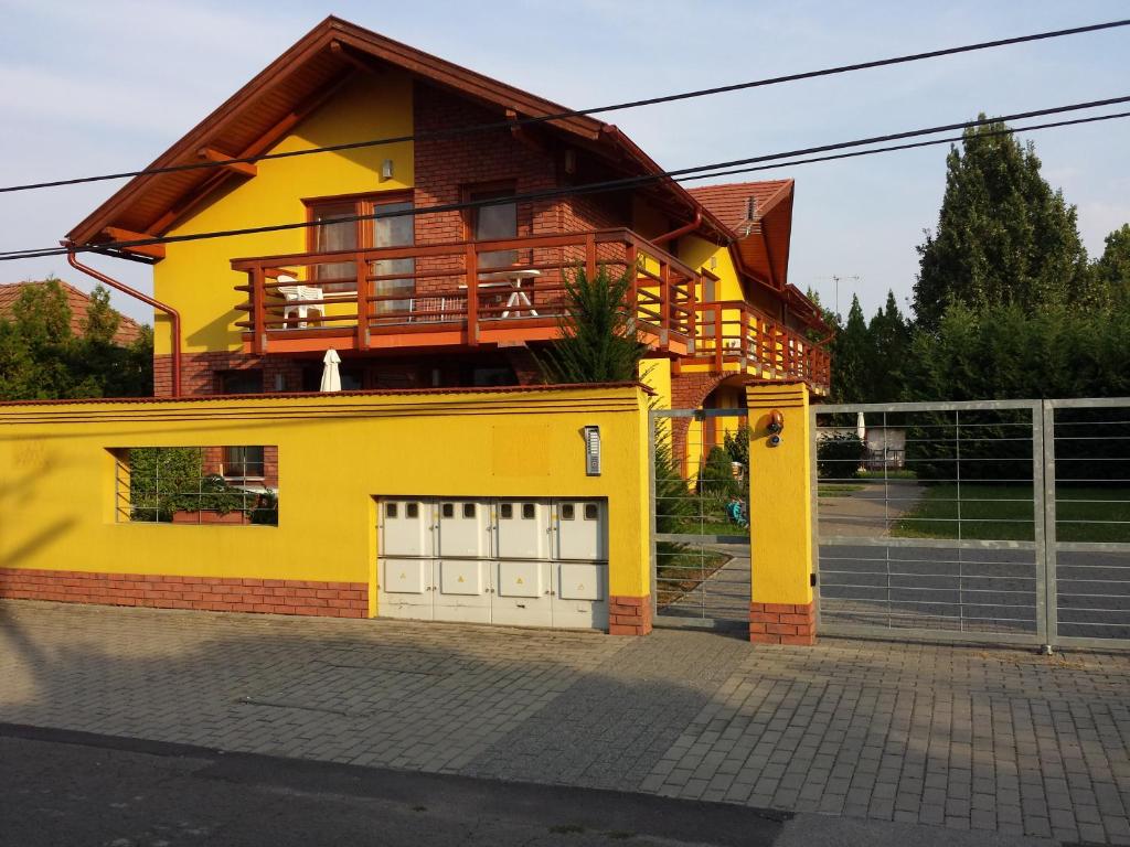 une maison jaune avec un balcon au-dessus dans l'établissement OKKER Apartman, à Gyula