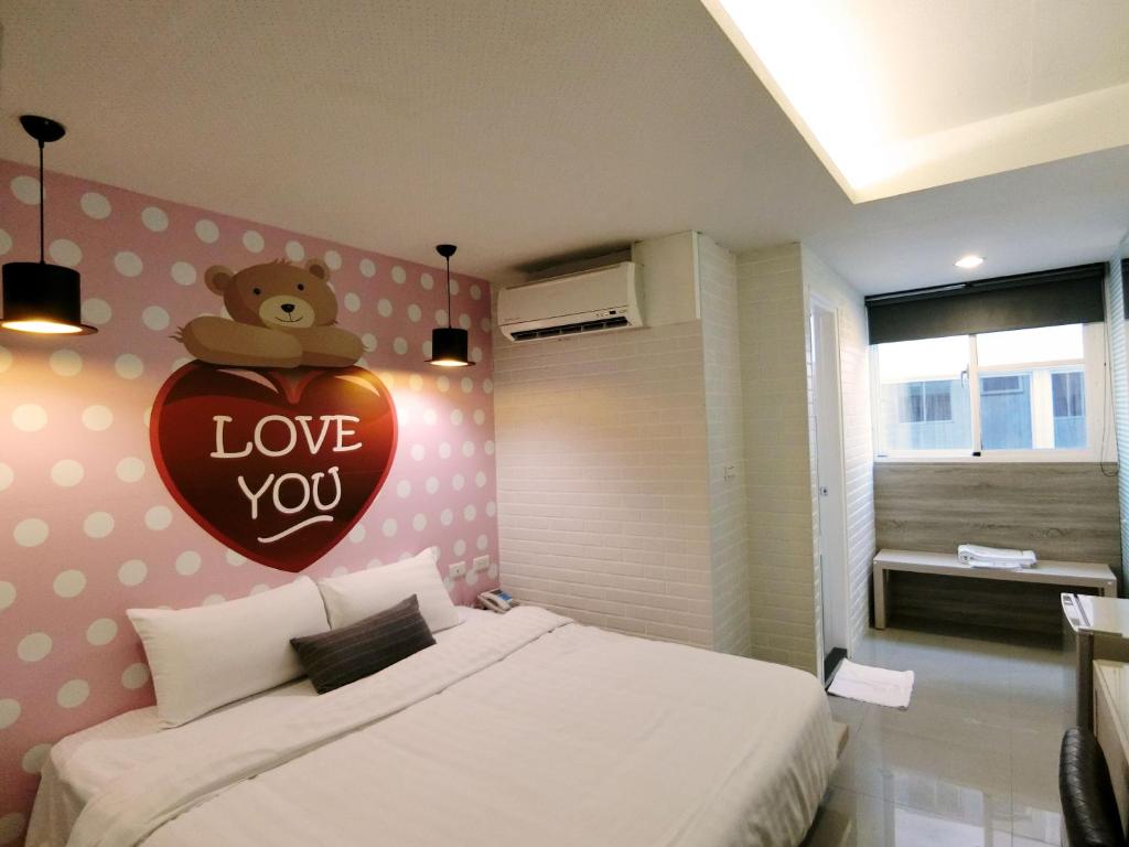 a bedroom with a heart with a teddy bear on the wall at S&amp;E Hotel in Tainan
